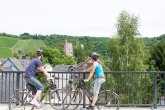 Radfahrer schauen von der Brücke auf die Burg Sommerau