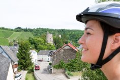 Fahrradfahrerin mit Helm vor der Burg Somnmerau